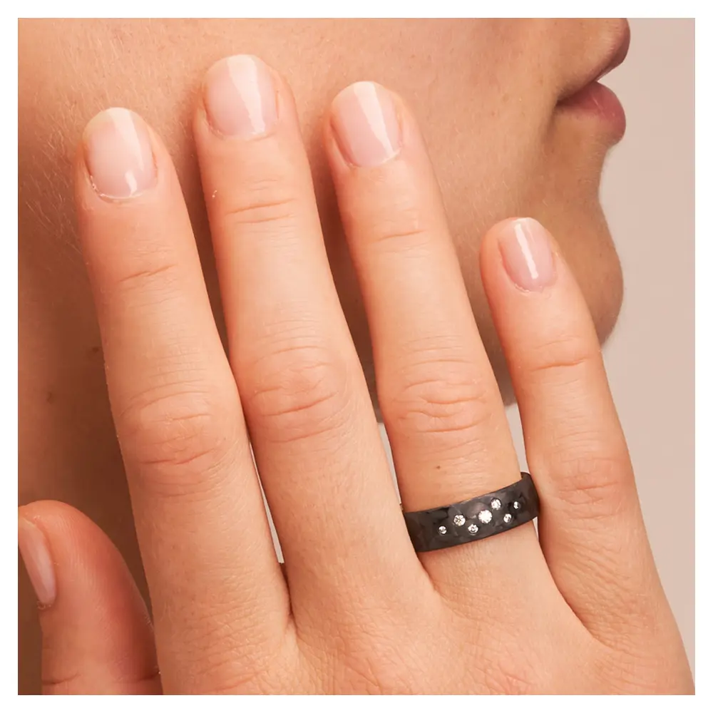 Eheringe aus Weißgold und Carbon mit Diamanten als Sternenhimmel auf Hand im Gesicht im Zoom