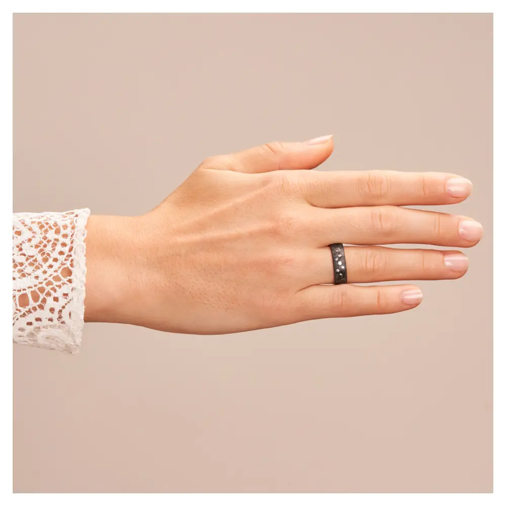 Eheringe aus Platin und Carbon mit Diamanten als Sternenhimmel auf Hand
