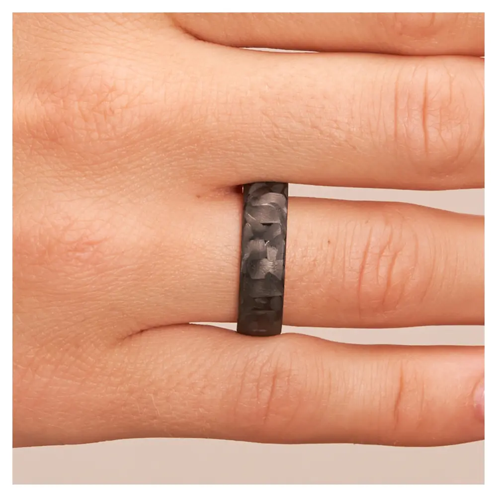 Eheringe aus Weißgold und Carbon auf Hand im Zoom