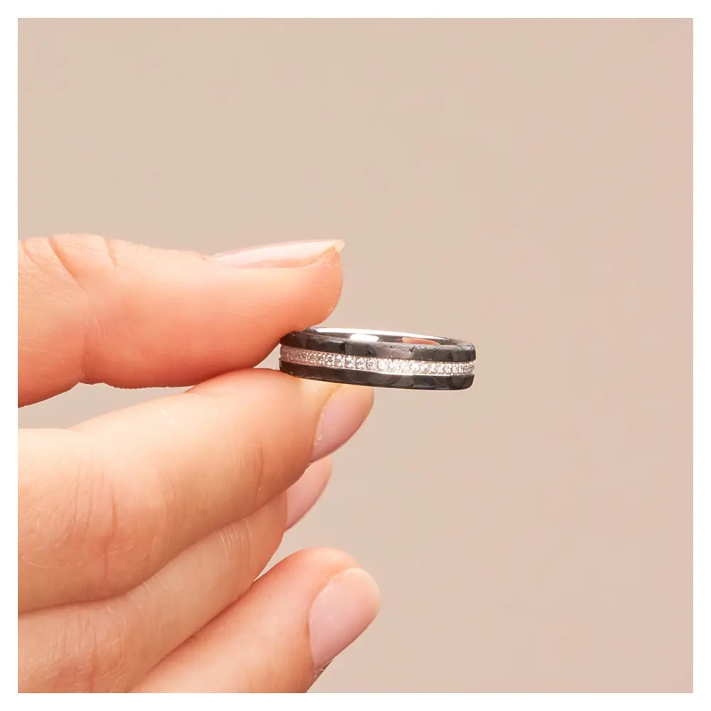 Eheringe aus Weissgold mit Carbon und 55 Diamanten in Ringschiene in Hand