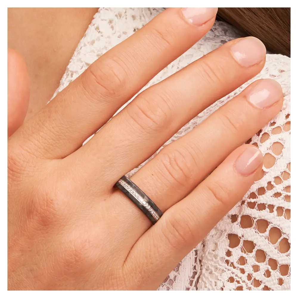 Eheringe aus Platin mit Carbon und 55 Diamanten in Ringschiene auf Hand am Gesicht im Zoom