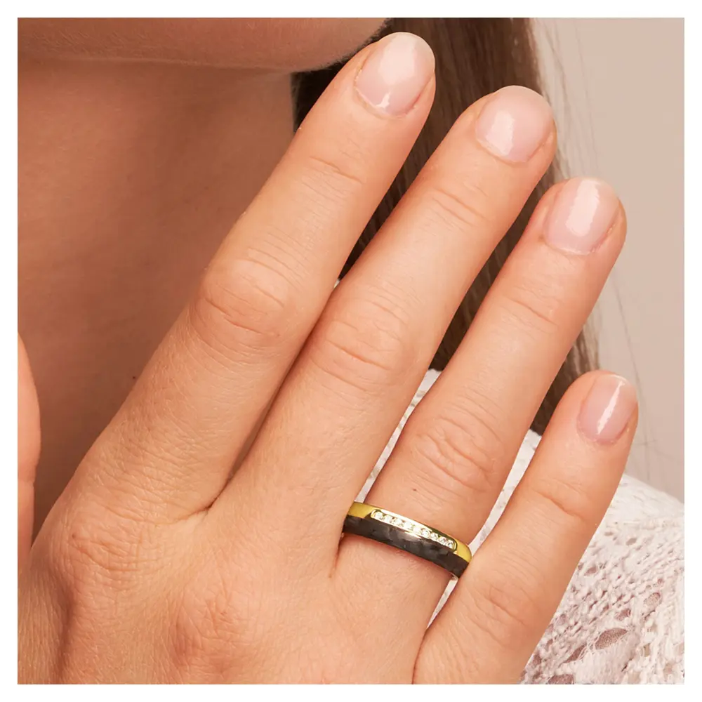 Eheringe aus poliertem Gelbgold mit Carbonstreifen und 9 Diamanten auf Hand am Gesicht im Zoom