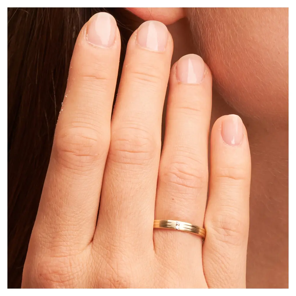 Schmale Trauringe aus Gelbgold mit 2 polierten Rillen und 2 Diamanten auf Hand im Zoom
