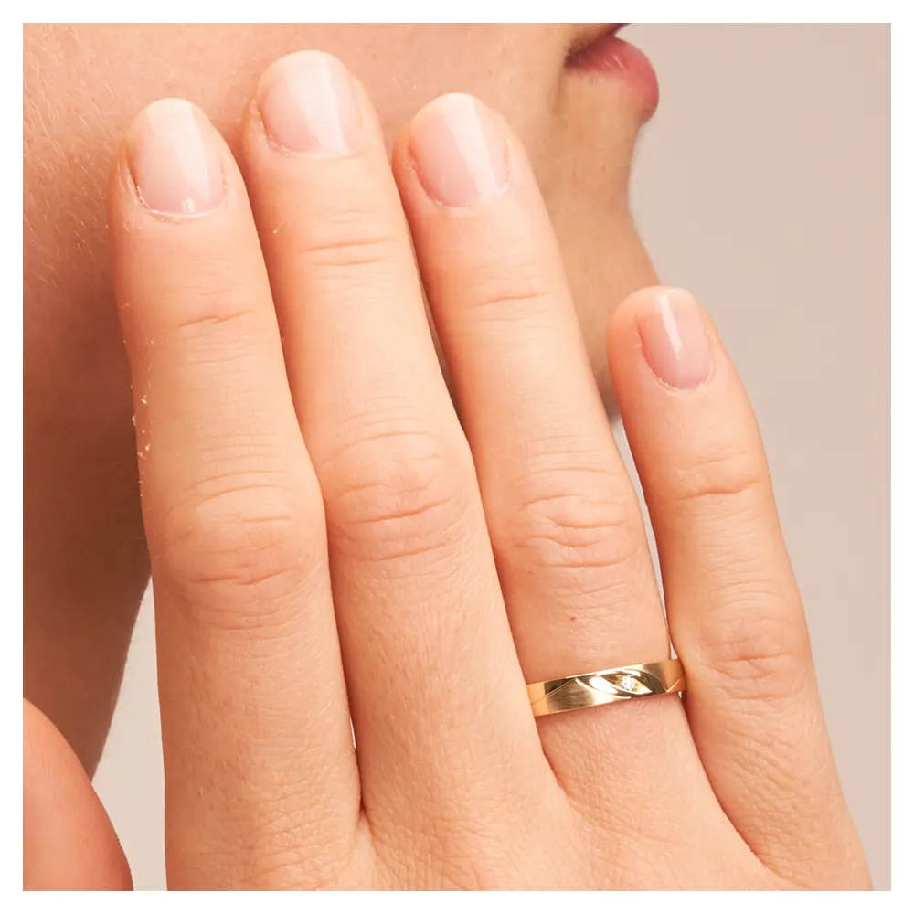 Gelbgold Trauringe mit geschwungenen Rillen und Diamant in Vertiefung auf Hand im Zoom