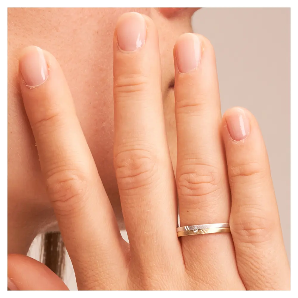 Trauringe aus Gelbgold und Weißgold schmal quermatt mit Diamant auf Hand im Zoom