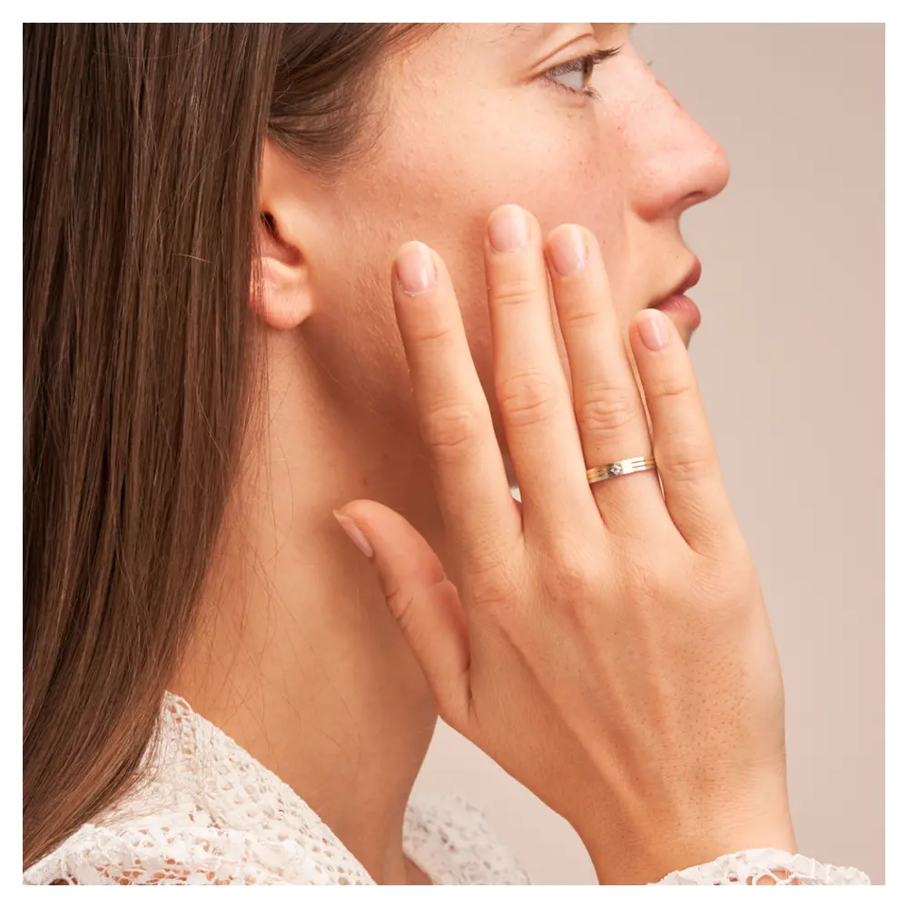 Trauringe aus Gelbgold und Weißgold schmal längsmatt mit Diamant auf Hand