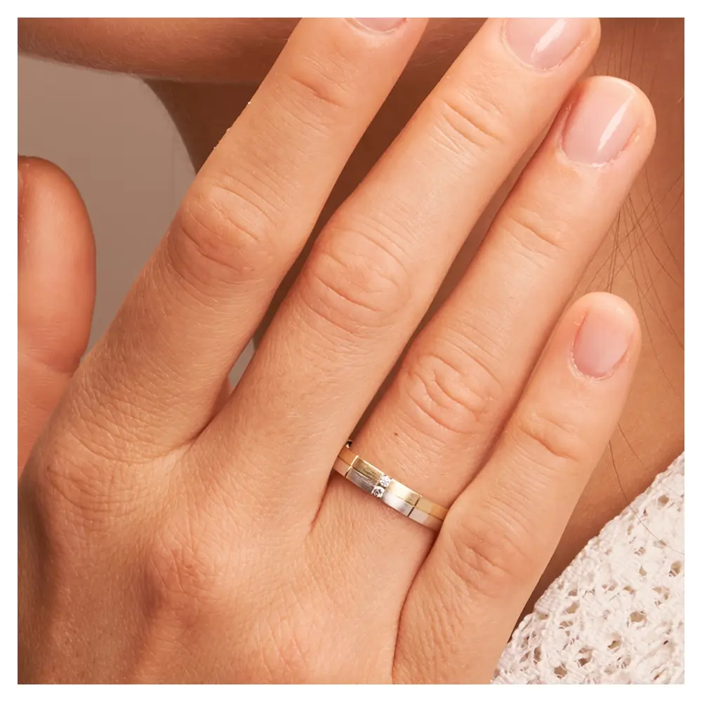 Trauringe aus Gelbgold und Weißgold mattiert mit 2 Diamanten und Rillen auf Hand im Zoom