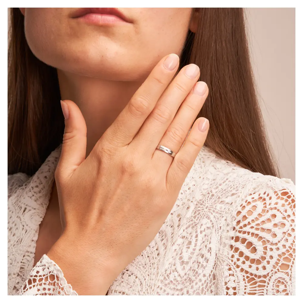 Mattierte Eheringe aus Platin mit Diamanten in augenförmiger Kerbe auf Hand