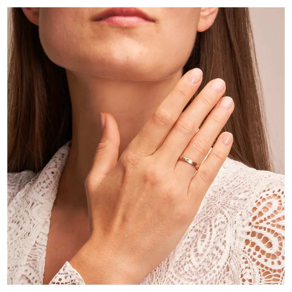 Trauringe aus Roségold mit Mattierung und geschwungenen Rillen und Diamant auf Hand
