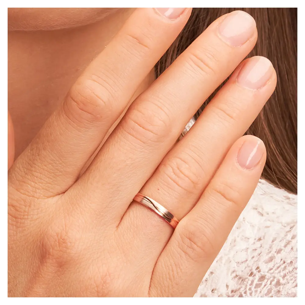 Trauringe aus Roségold mit Mattierung und geschwungenen Rillen auf Hand im Zoom