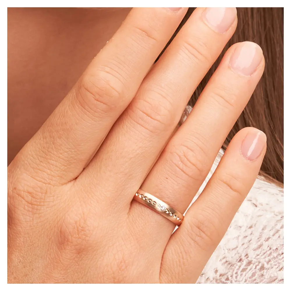 Längsmatte Eheringe aus Rosègold mit Diamanten und Millgriff auf Hand im Zoom