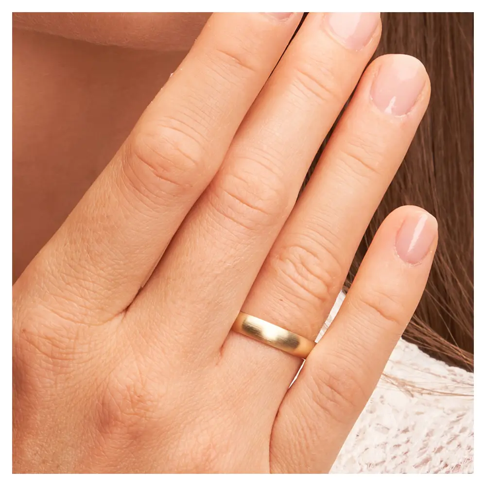 Mattierte Eheringe aus Gelbgold mit Millgriff auf Hand im Zoom
