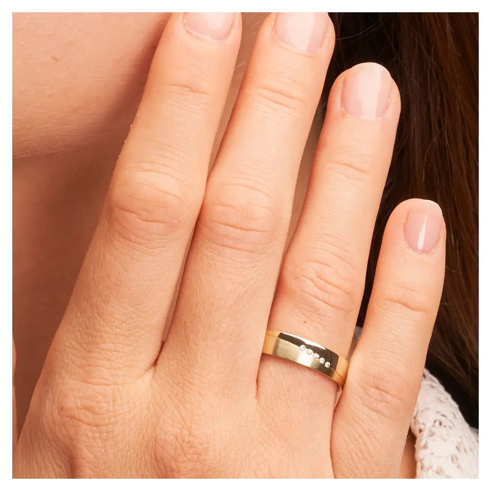 Trauringe aus Gelbgold mit 5 Diamanten Polierung und Mattierung auf Hand im Zoom