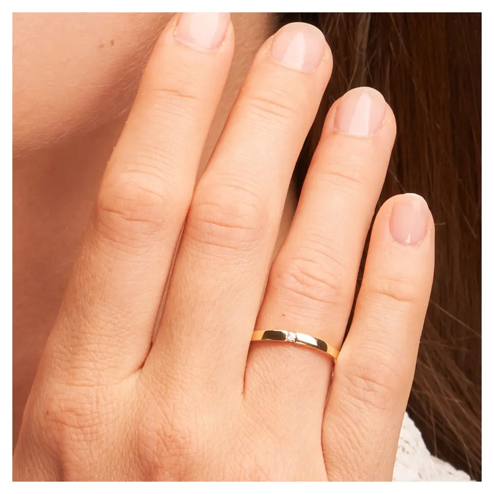 Trauring aus Gelbgold mit Polierung und flachem Profil und Diamant auf Hand im Zoom