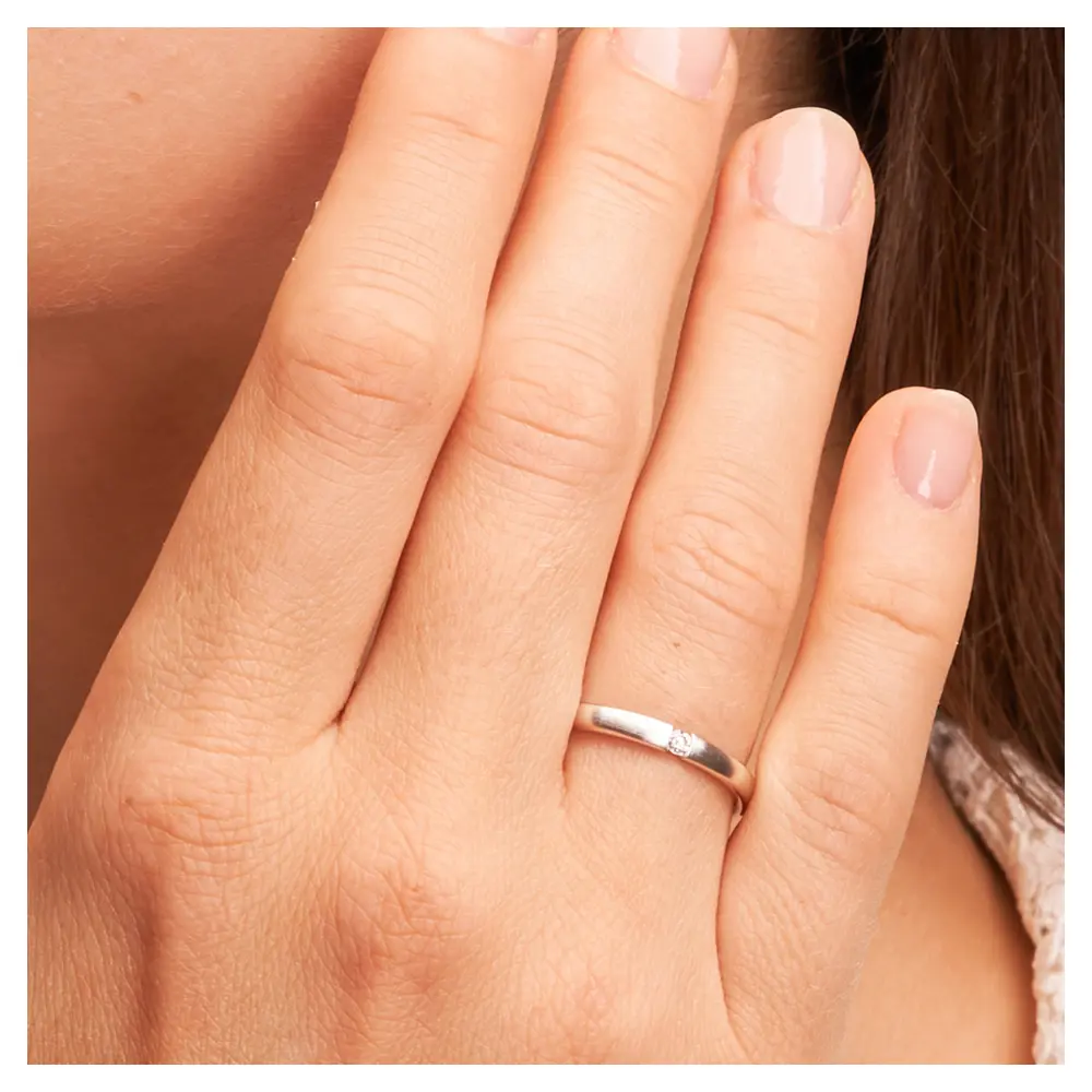 Schmale Eheringe aus Weissgold mit Diamanten und Längsmattierung auf Hand im Zoom