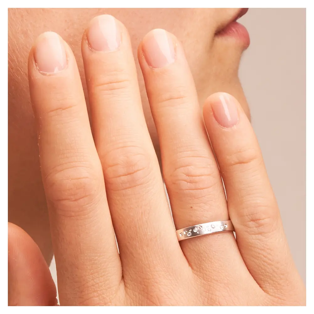 Matte Trauringe aus Weissgold mit Diamanten als Sternenhimmel auf Hand im Zoom