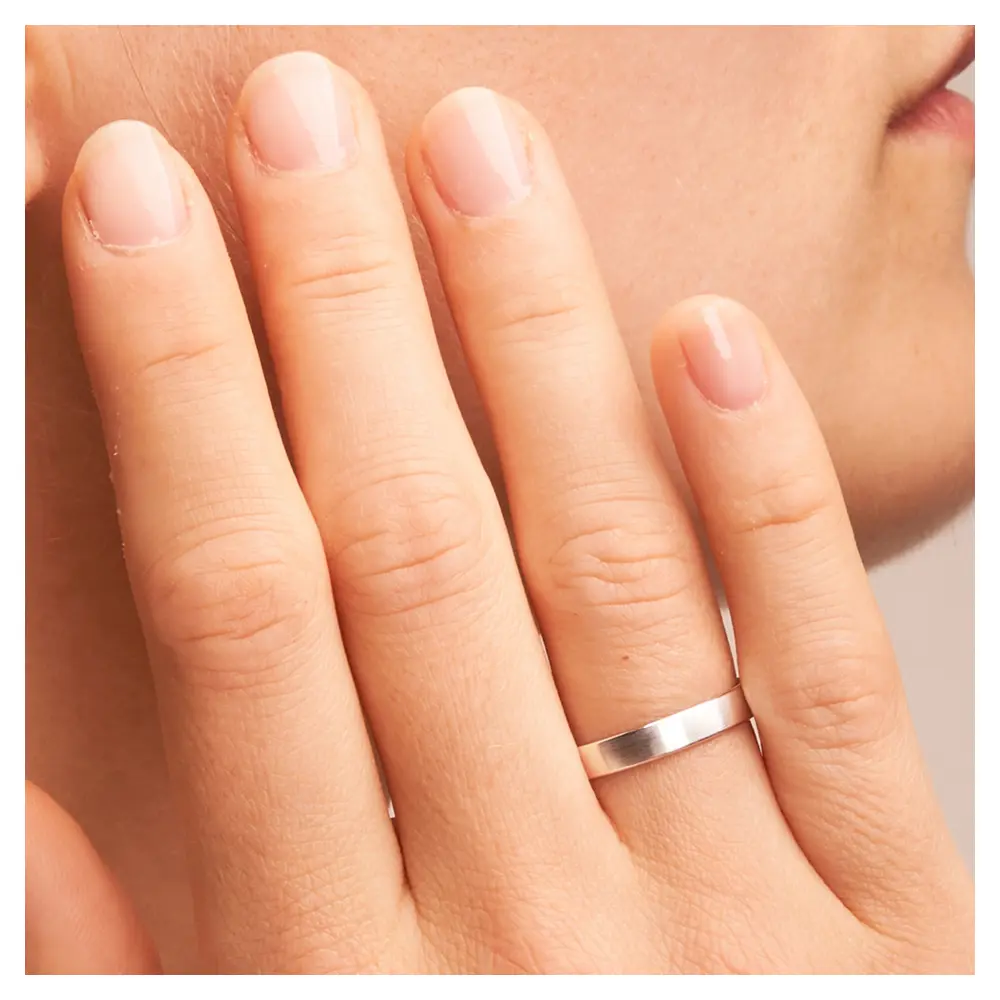 Matte Trauringe aus Weissgold auf Hand im Zoom