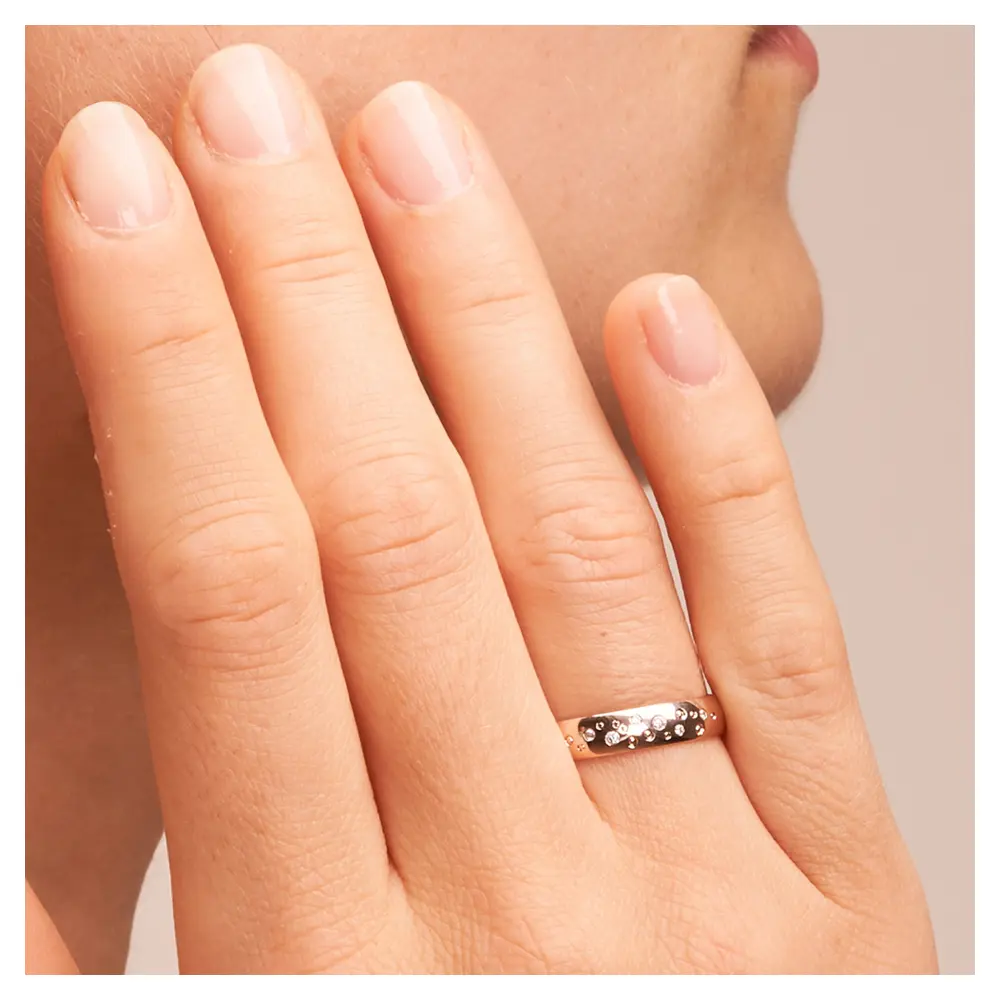 Polierte Trauringe aus Roségold mit Diamanten im Sternenhimmel Design auf Hand im Zoom
