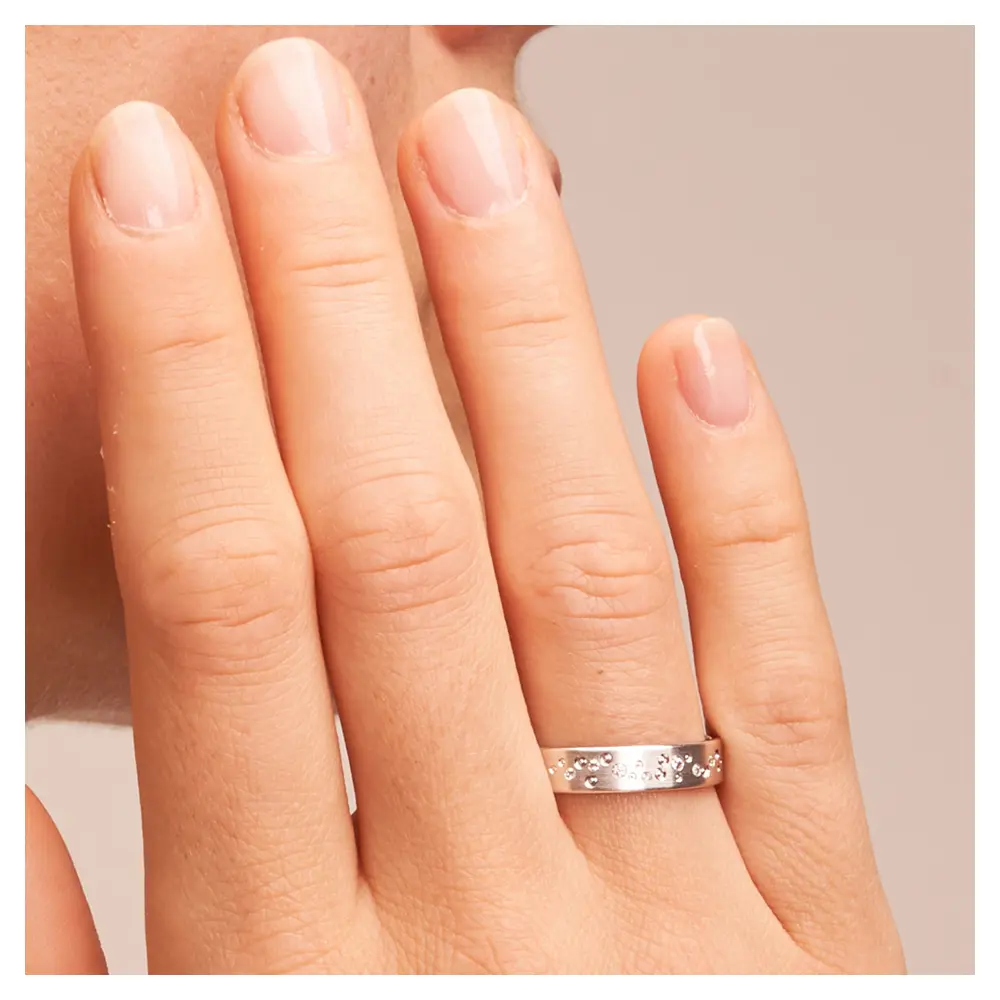 Mattierte Eheringe aus Weissgold mit 7 Diamanten und Muster aus Kreisen auf Hand im Zoom