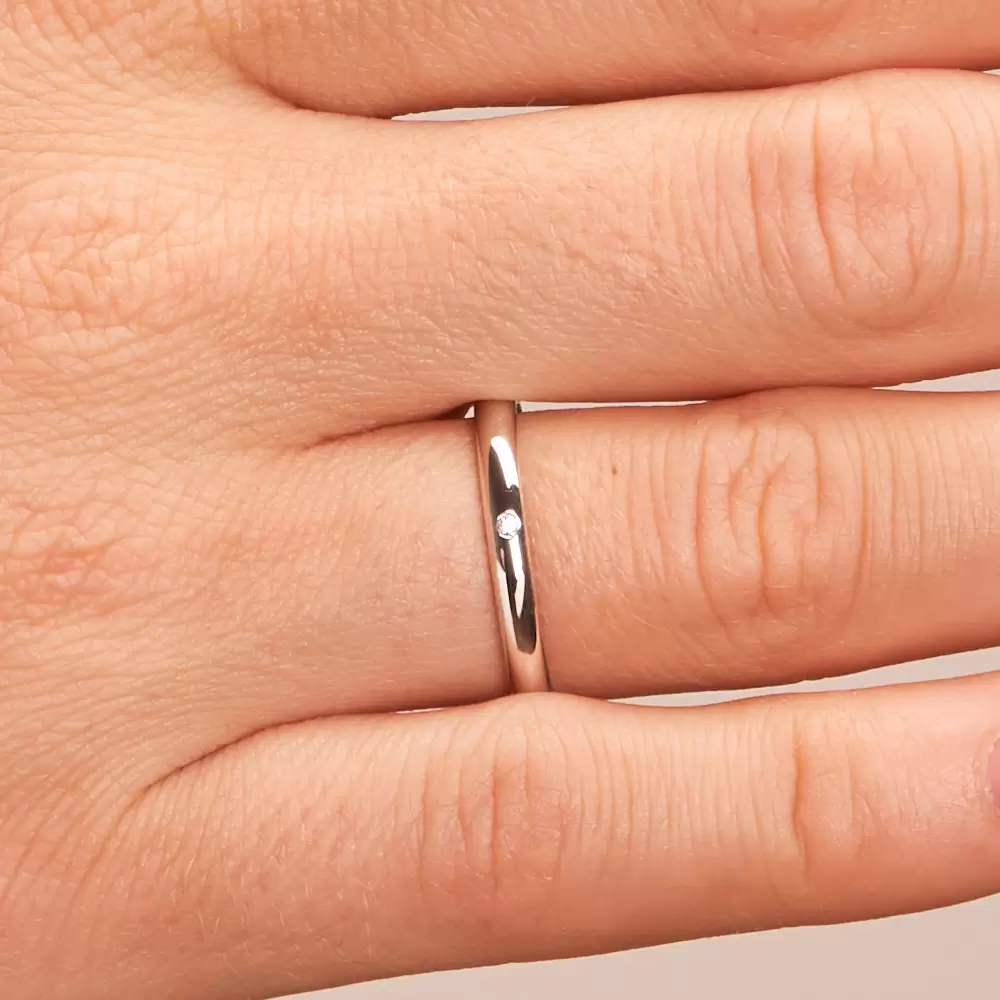 2,5 mm breite Weißgold Eheringe mit 0,01 Karat Diamant auf Hand im Zoom