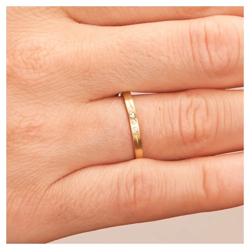 Gelbgold Eheringe matt mit Muster und drei Diamanten auf Hand im Zoom