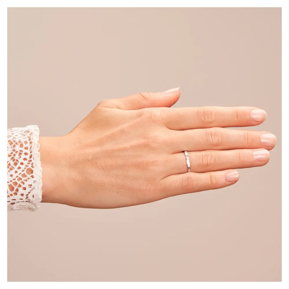 Sandmattierte Eheringe aus Platin mit Muster und Diamanten auf Hand
