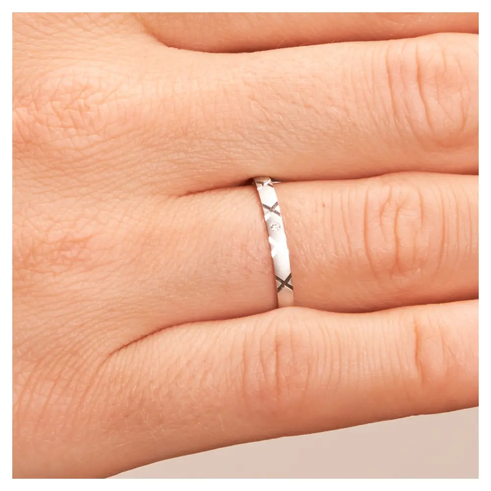 Sandmattierte Eheringe aus Platin mit Muster und Diamanten auf Hand im Zoom