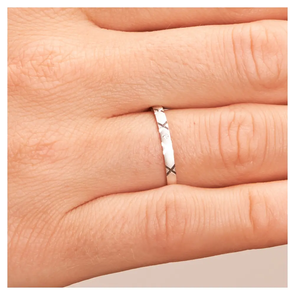 Ehering aus Weißgold sandmatt mit Diamanten und Kreuzmuster auf Hand im Zoom
