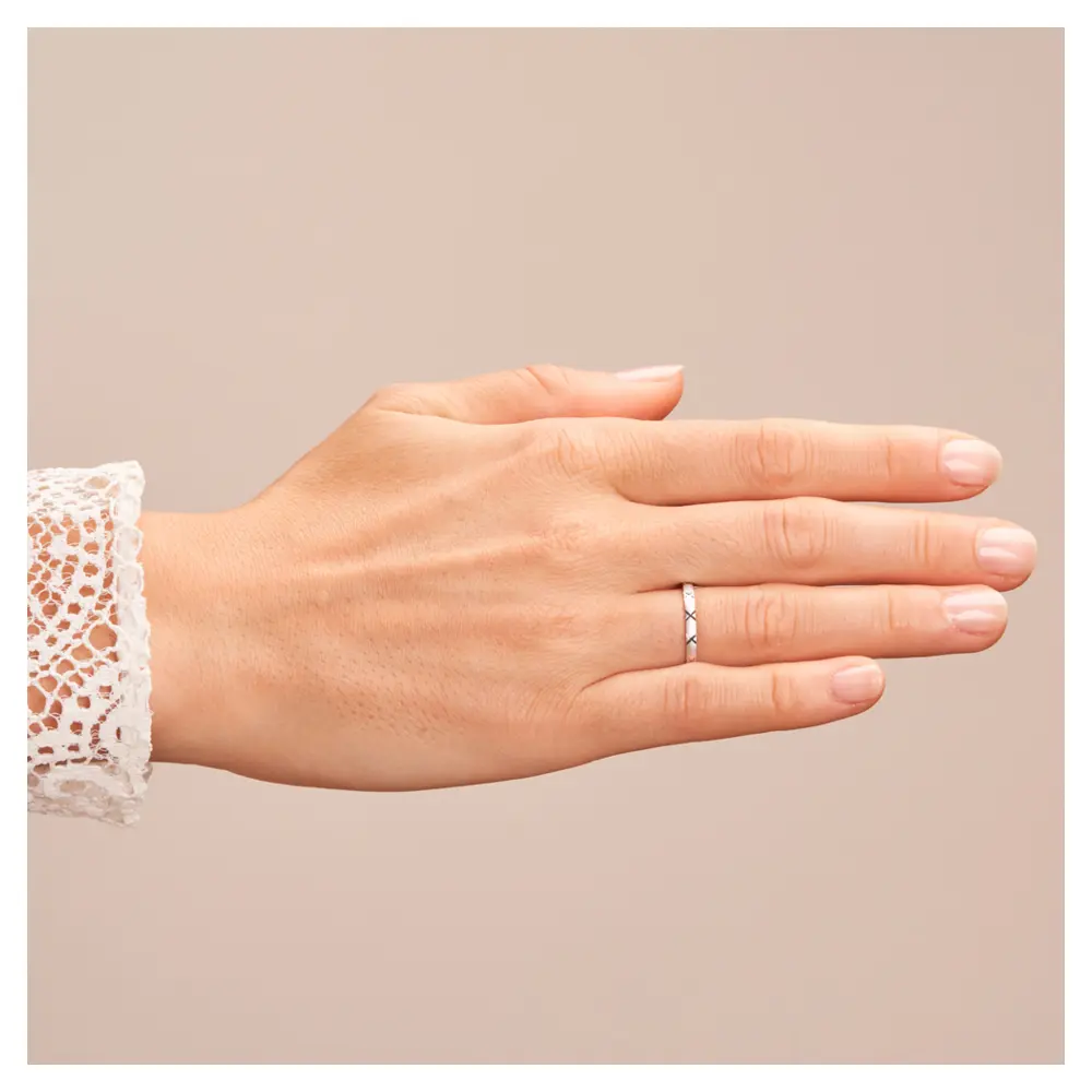 Sandmattierte Eheringe aus Platin mit Muster auf Hand im Zoom
