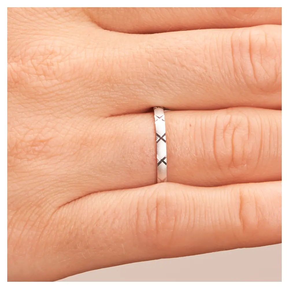 Sandmattierte Eheringe aus Platin mit Muster auf Hand im Zoom