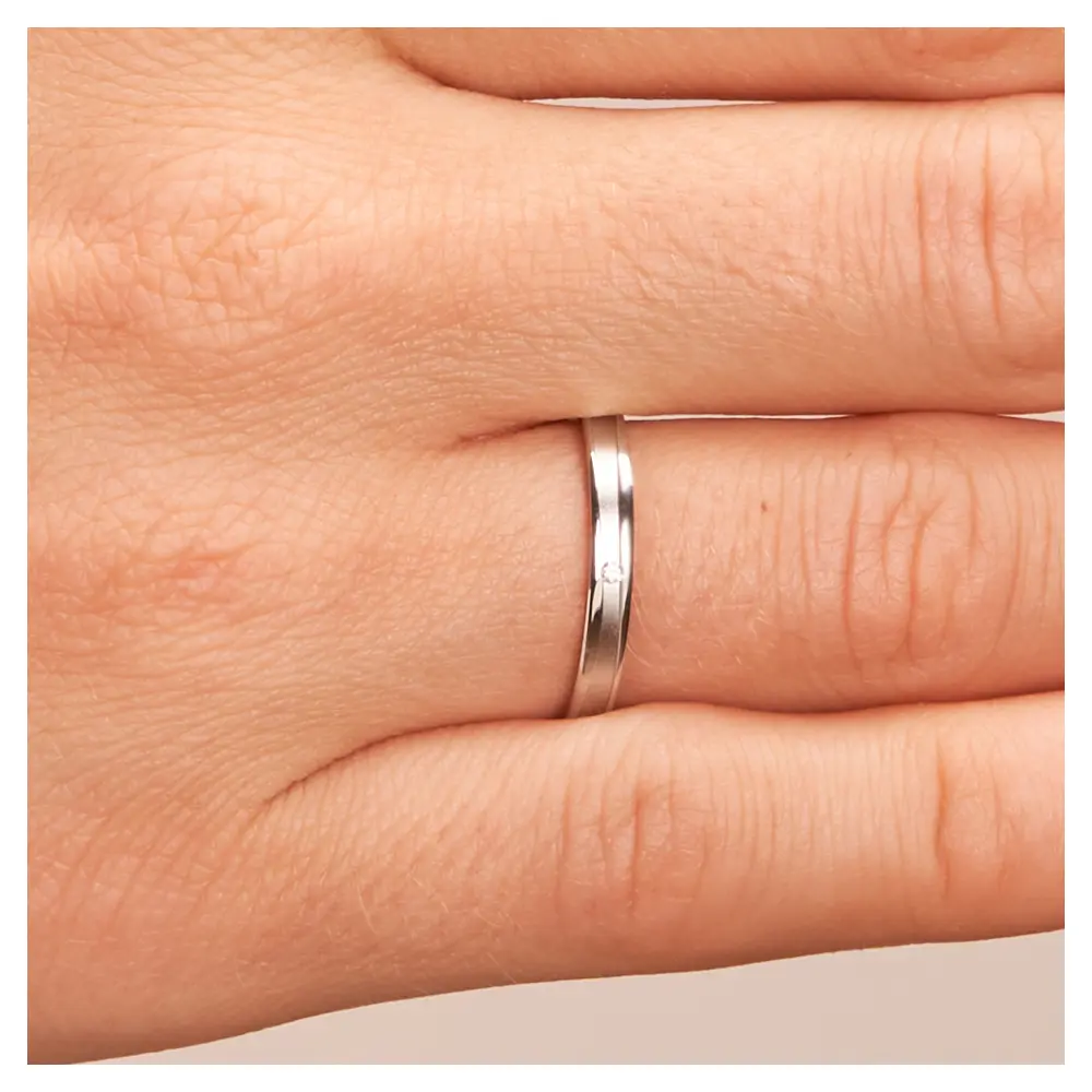 Eheringe aus Platin mit Diamanten in sandmattierter Rille auf Hand im Zoom
