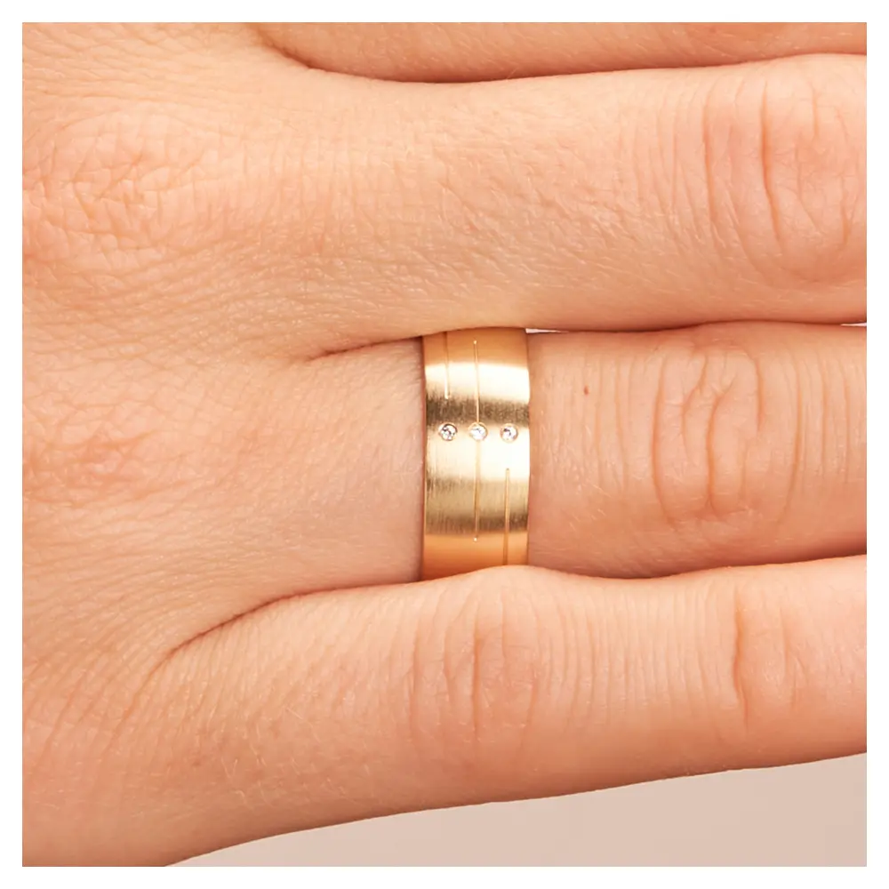 Gelbgold Trauring breit matt mit Rillenmuster und 3 Diamanten auf Hand im Zoom