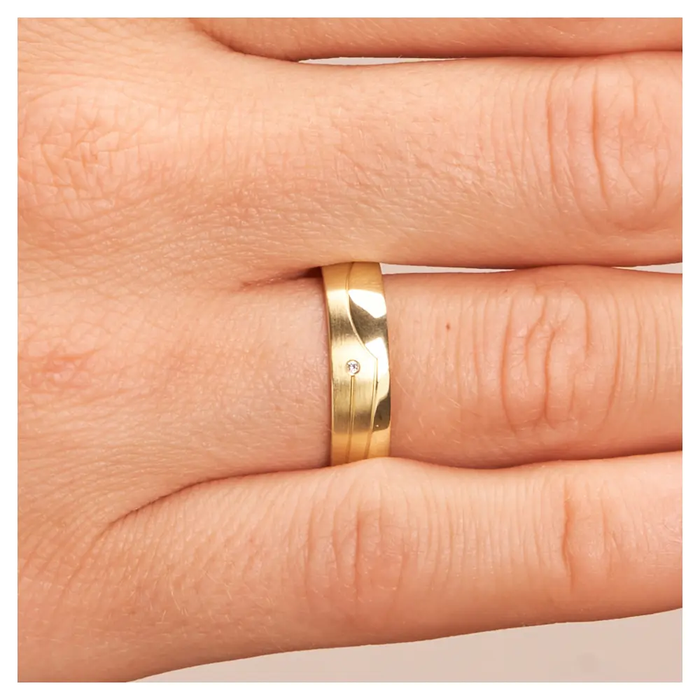 Gelbgold Trauring matt poliert mit Rillendesign und Diamant auf Hand im Zoom
