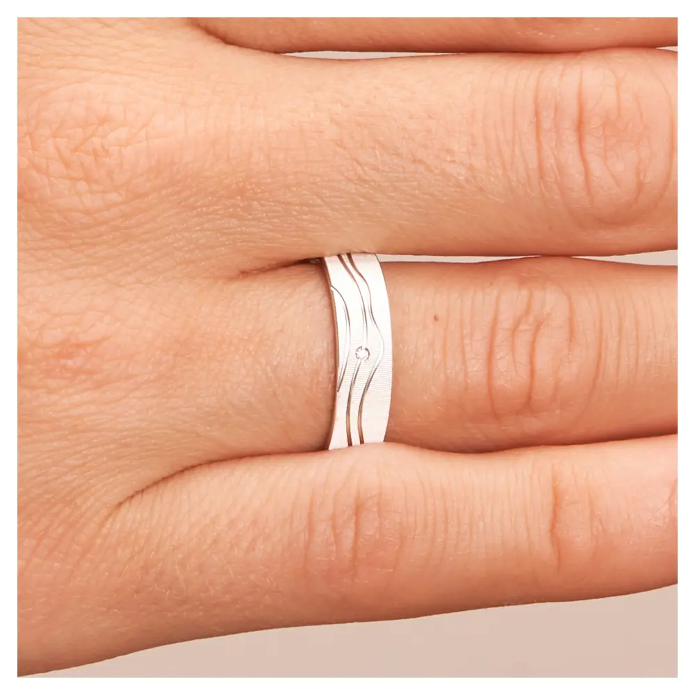 Strukturierter Weissgold Trauring mit Diamant und polierten Rillen auf Hand im Zoom