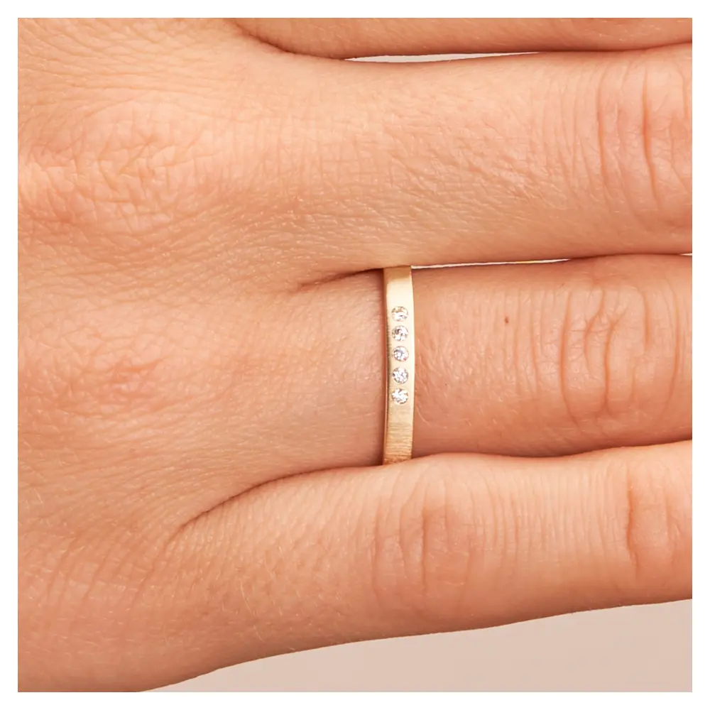 Schmaler Ehering aus Gelbgold mit 5 Diamanten und Quermattierung auf Hand im Zoom