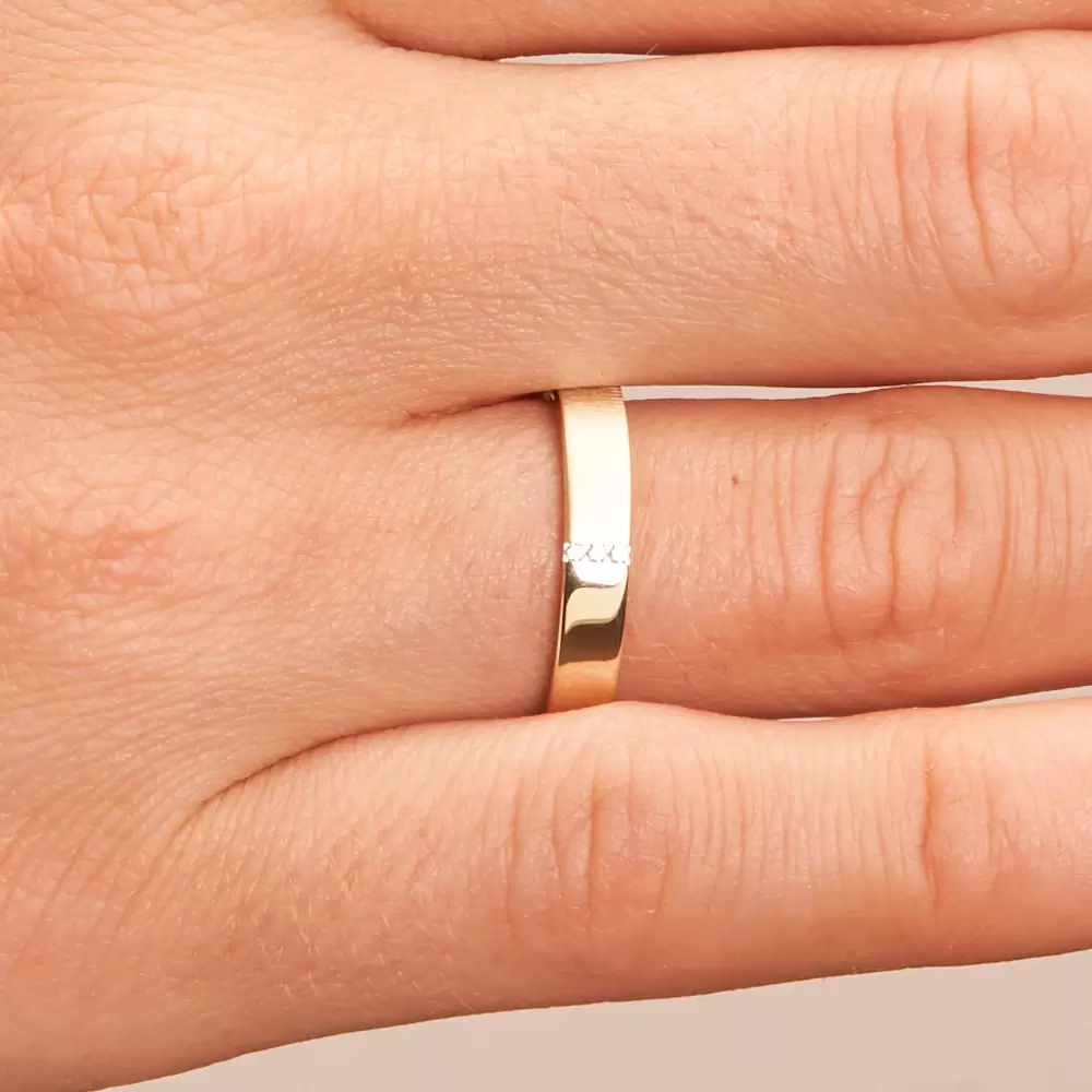 Halbmatter und halbpolierter Ehering aus Gelbgold mit 3 kanalgefassten Diamanten auf Hand im Zoom