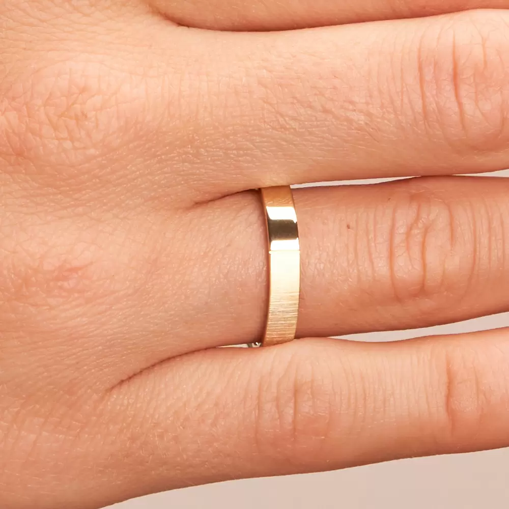 Halbmatter und halbpolierter Ehering aus Gelbgold auf Hand im Zoom