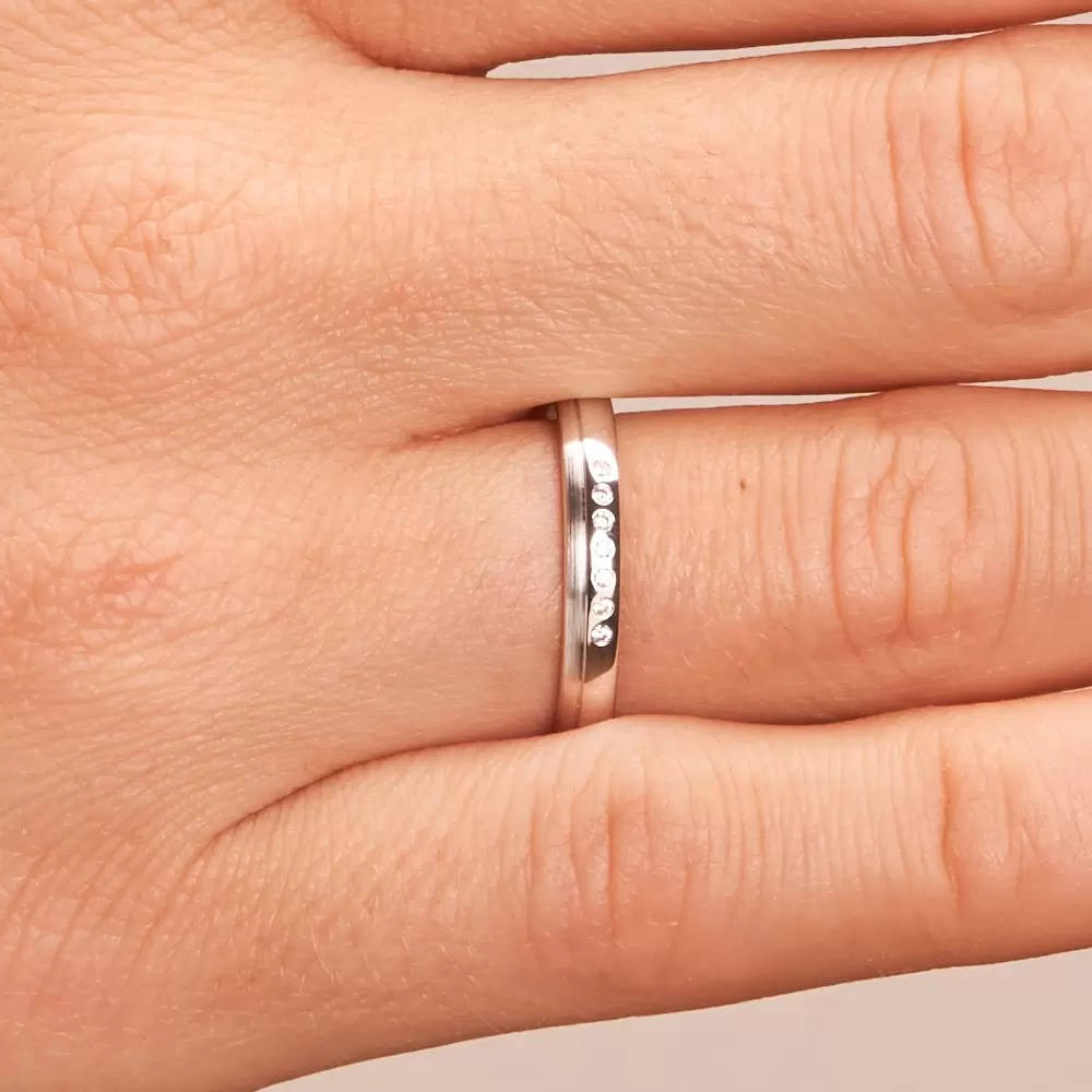 3 mm breite Weissgold Ehering mit 7 einzeln gefassten Diamanten auf Hand im Zoom