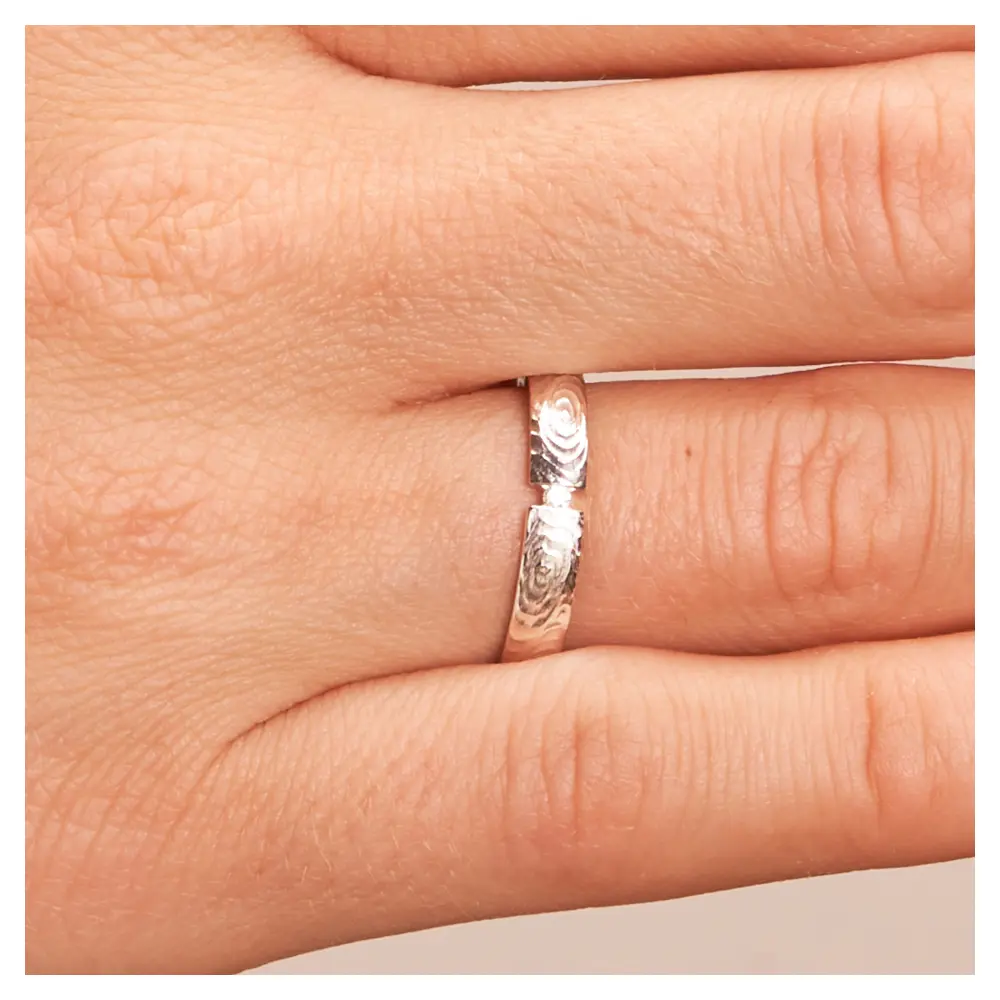 Weißgold Eheringe mit matter Strukturierung und Diamant in Spannfassung auf Hand im Zoom