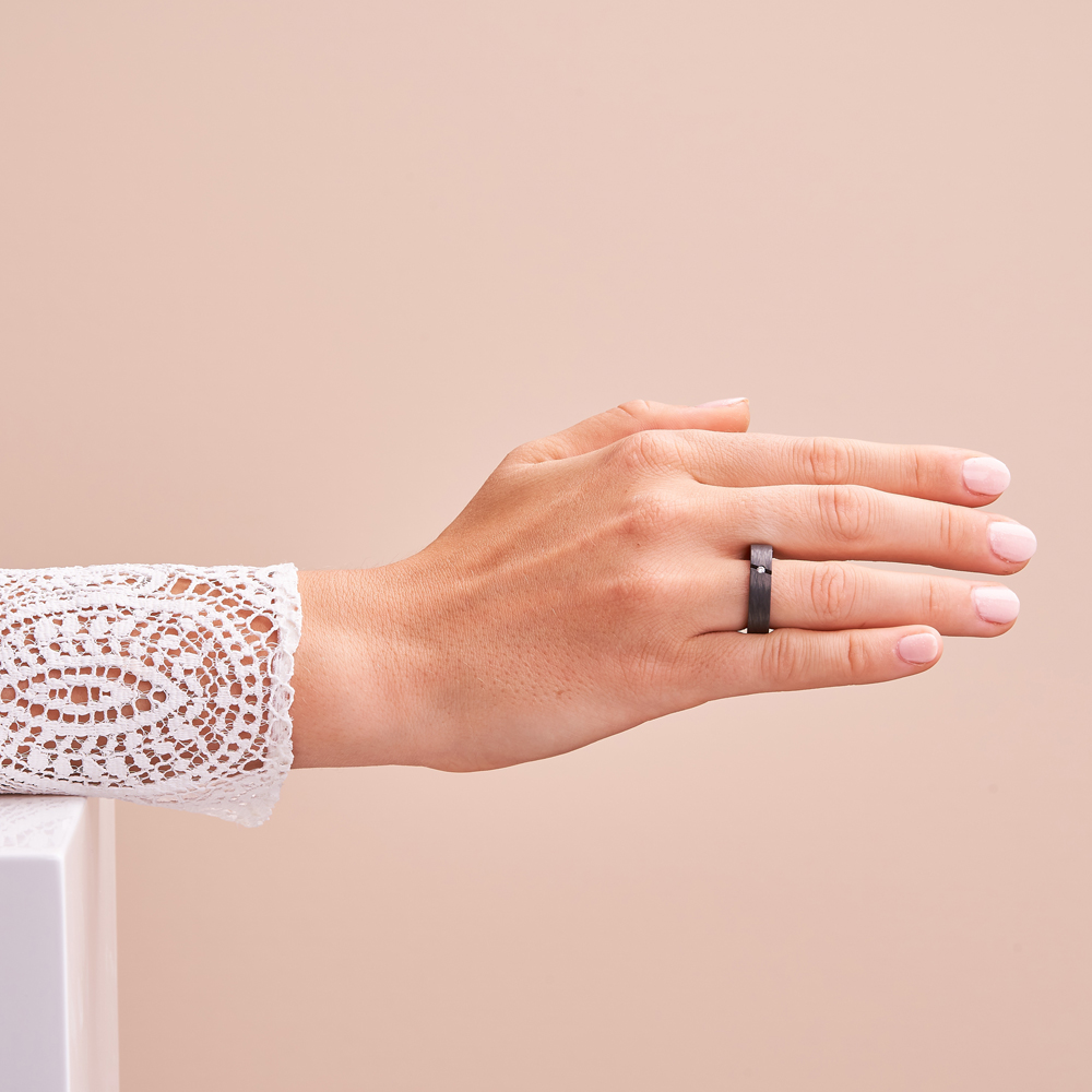 Aufnahme von schwarzen Trauringen aus Carbon mit Diamanten in schräger Fassung auf Hand