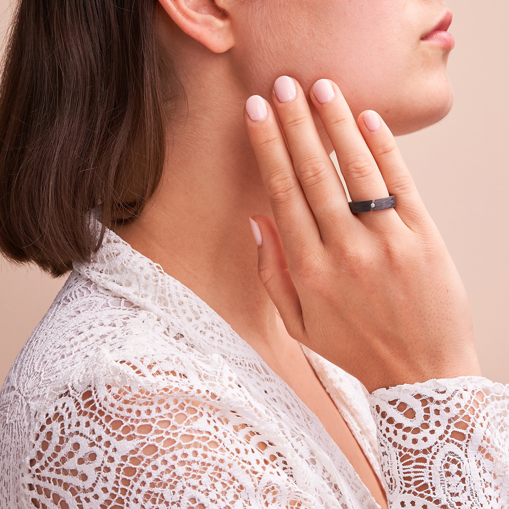 Aufnahme von schwarzem Verlobungsring aus Carbon mit Diamanten in schräger Fassung auf Hand