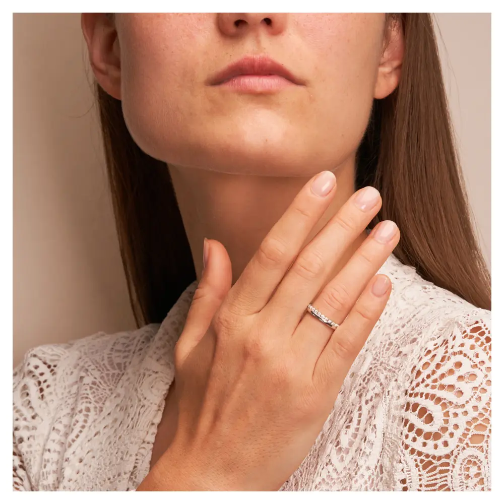 Polierte Eheringe aus rhodiniertem Silber 925 mit Zirkoniaband auf Hand am Gesicht