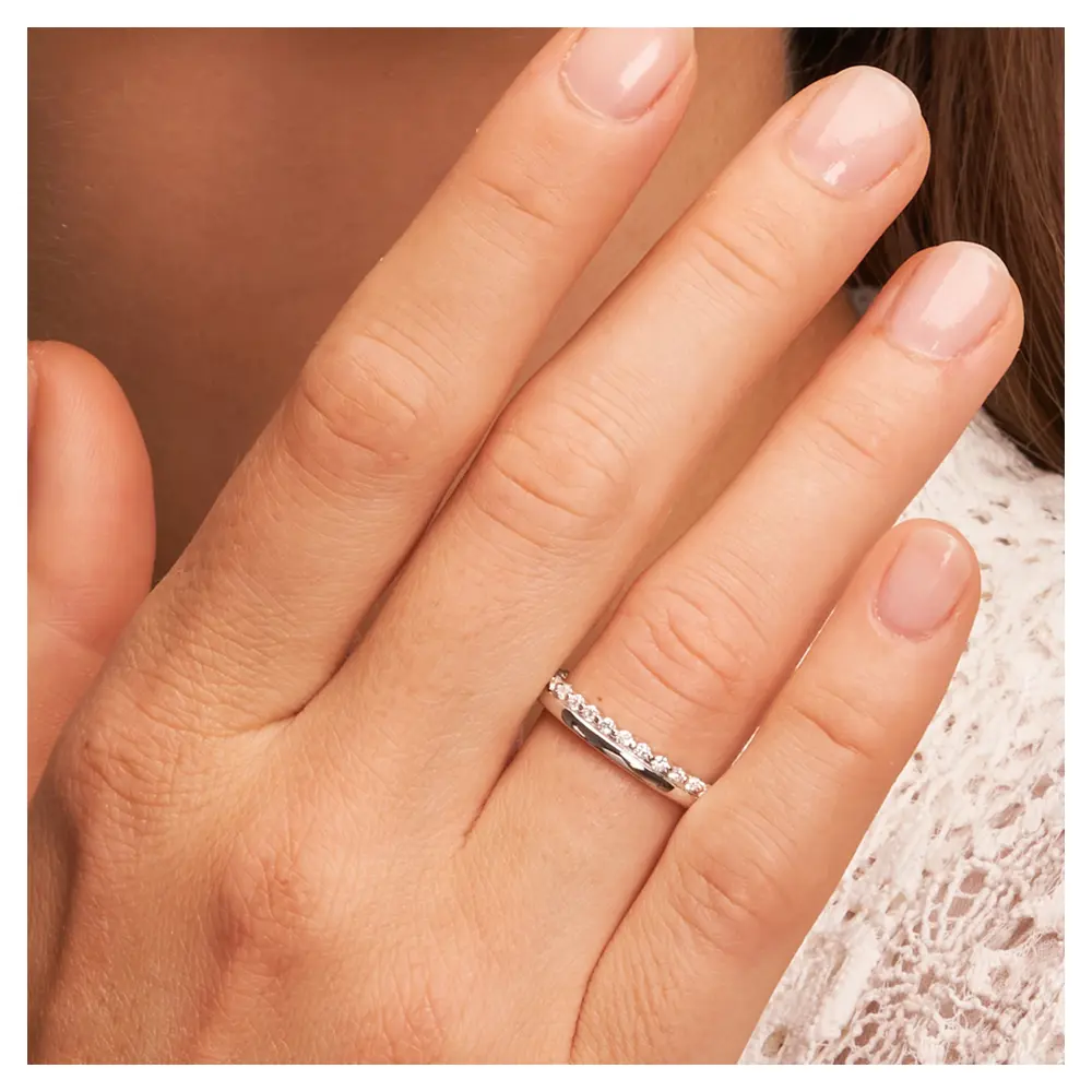 Polierte Eheringe aus rhodiniertem Silber 925 mit Zirkoniaband auf Hand am Gesicht im Zoom