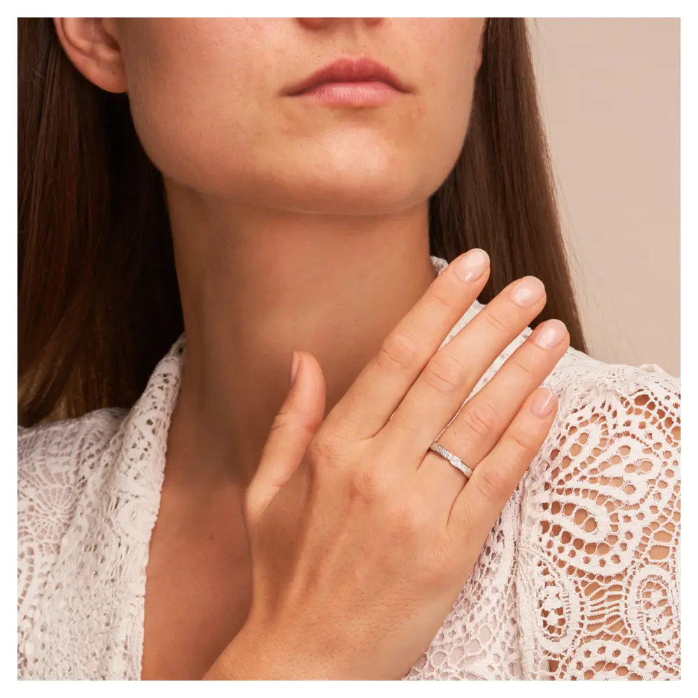 Eheringe aus rhodiniertem Silber 925 mit Zirkonia und Strukturierung auf Hand am Gesicht im Zoom