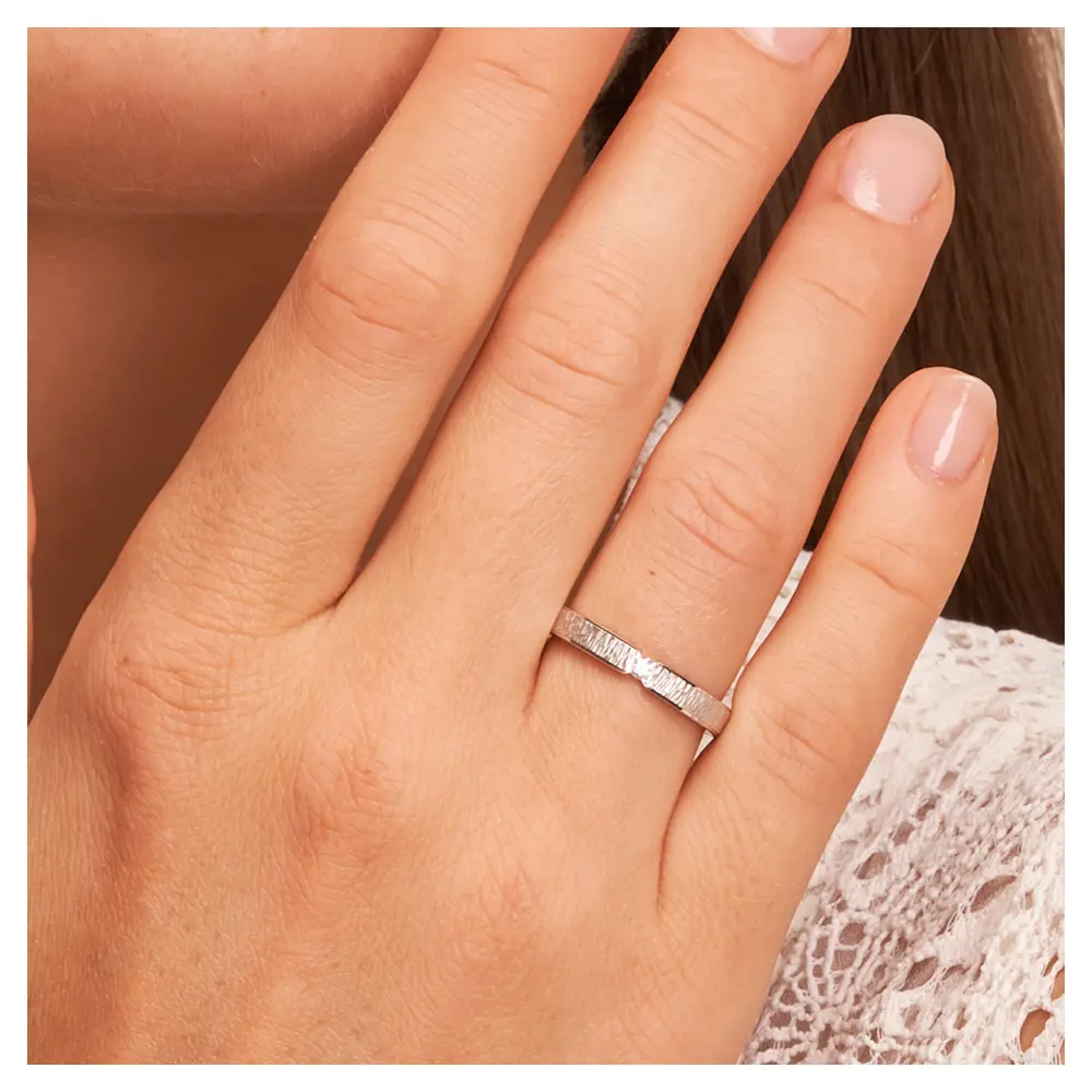 Eheringe aus rhodiniertem Silber 925 mit Zirkonia und Strukturierung auf Hand am Gesicht im Zoom