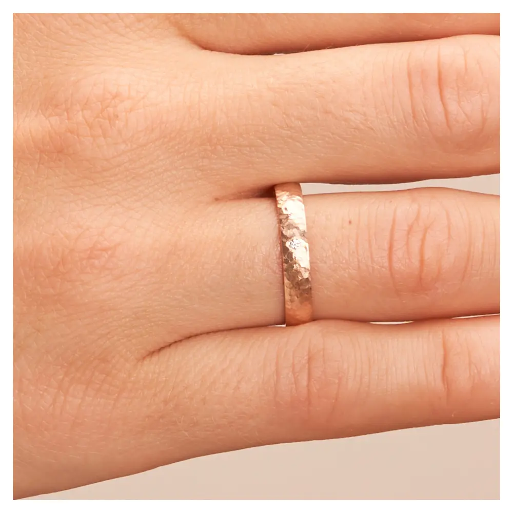 Ehering aus Roségold in 4 mm mit Hammerschlag und Diamanten auf Hand im Zoom