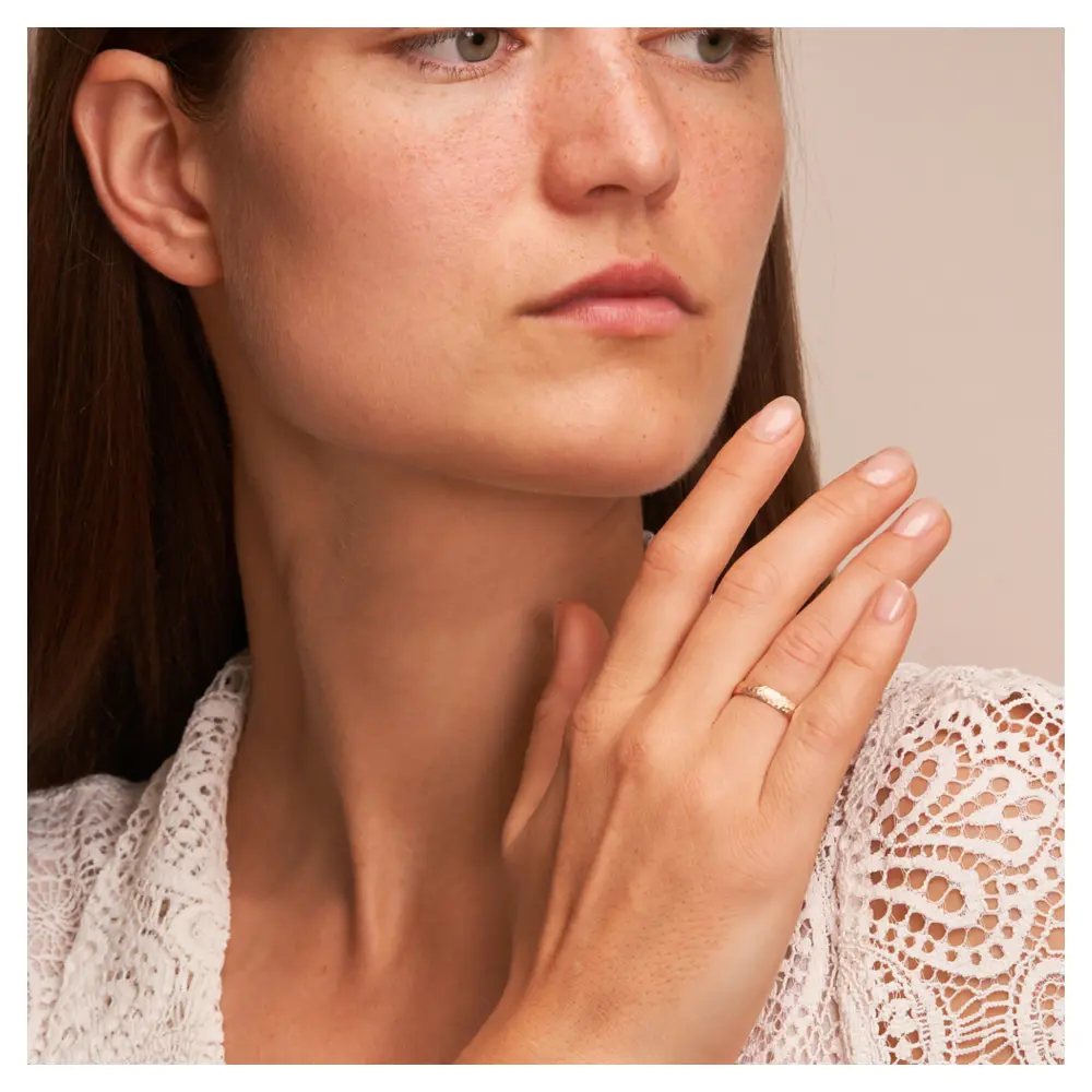 Eheringe aus Roségold mit Hammerschlag und Diamanten auf Hand am Gesicht