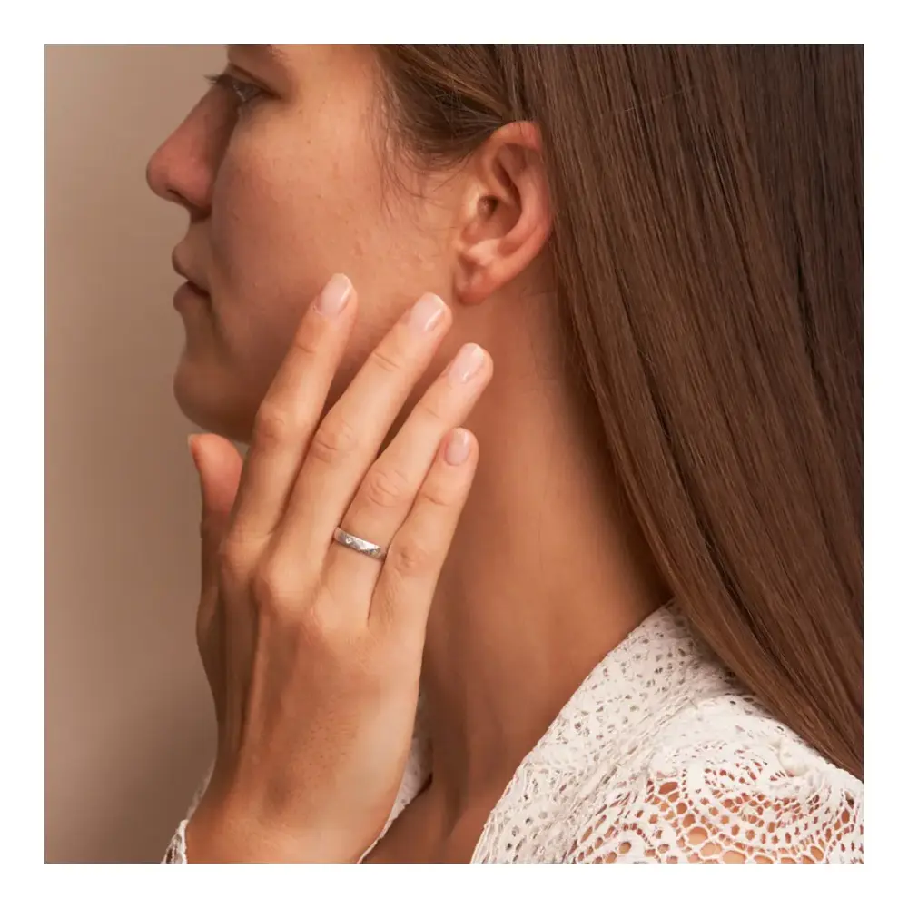 Eheringe aus Weissgold in 4 mm mit Hammerschlag und Diamanten auf Hand am Gesicht