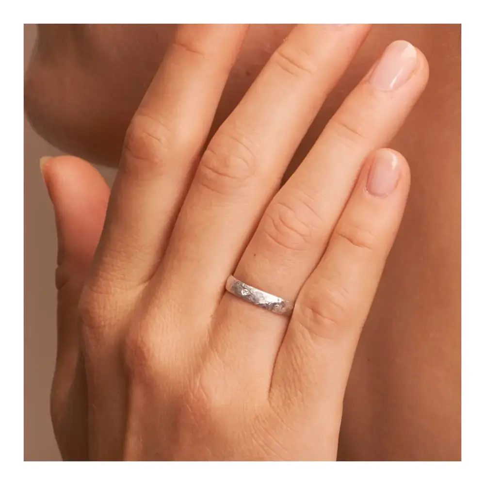 Eheringe aus Weissgold in 4 mm mit Hammerschlag und Diamanten auf Hand am Gesicht im Zoom