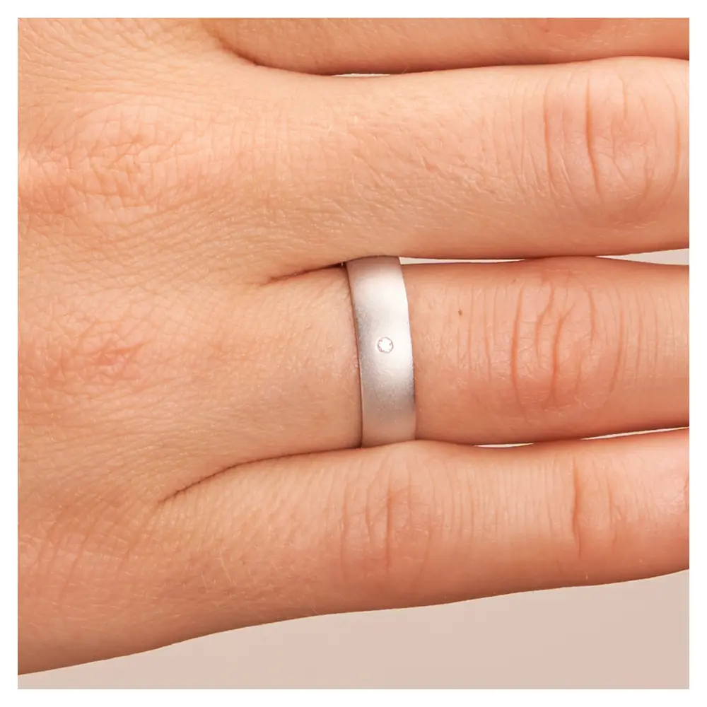Weissgold Trauring sandmatt mit Diamanten und 5 mm Breite auf Hand im Zoom
